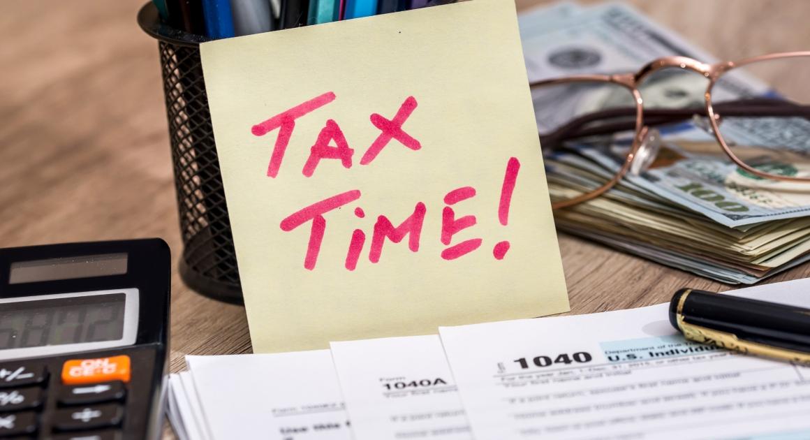 Tax time sticky note with calculator and tax forms